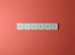 Free Close-up of keyboard keys spelling 'BACKUP' placed on a coral-colored surface. Stock Photo