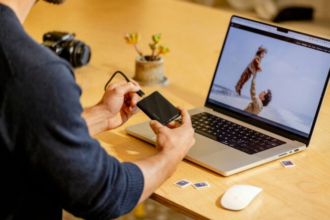 A man sitting at a table with a laptop and cell phone