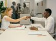 Free Business professionals completing a successful deal with a handshake in a modern office setting. Stock Photo