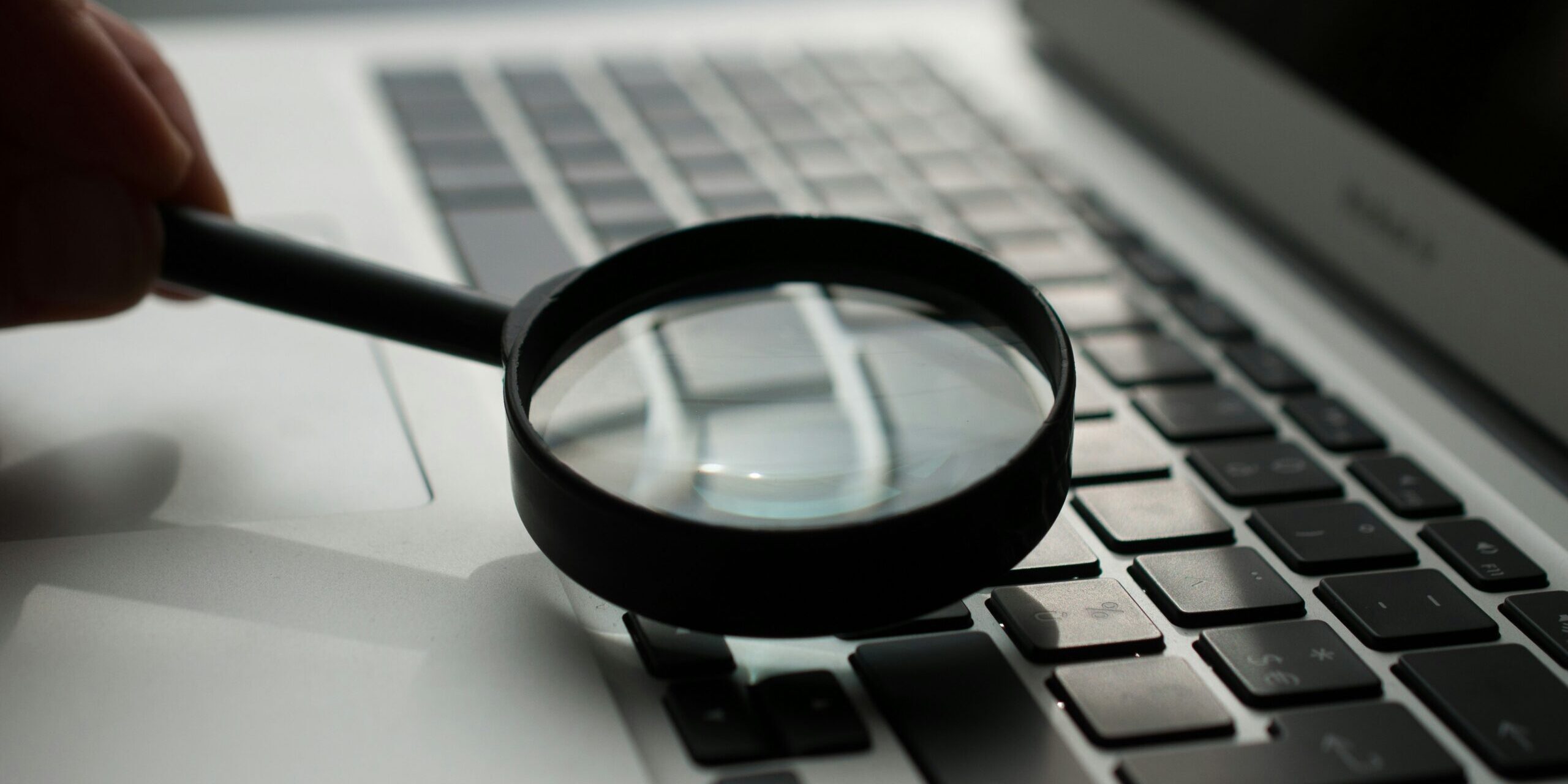 magnifying glass near gray laptop computer