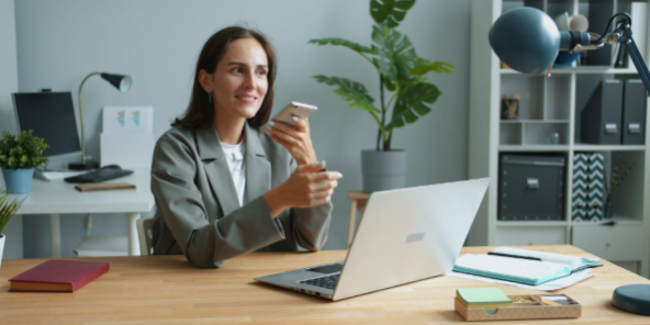 lady holding phone while working on a laptop